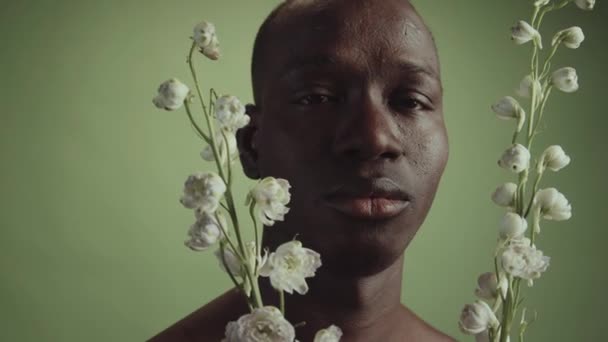 年轻的黑人男子手持白花 睁开眼睛看着相机 这幅极小的特写镜头 — 图库视频影像