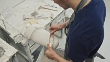 Uzuv protezi için özel delinmiş el aletleri ile alçıyı şekillendiren çalışma masasında duran modern profesyonel zanaatkârın yüksek açılı görüntüsü
