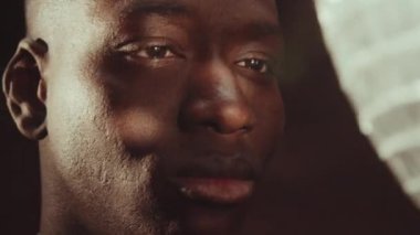 Parlak disko topunun önünde spot ışıklarıyla parlayan yakışıklı Afrikalı Amerikalı adamın yakın plan portresi.