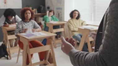 Öğlenden sonra bulanık ergen öğrencilere ders veren kırpılmış erkek öğretmenin orta bölümü.