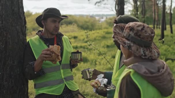 Mediana Tres Jóvenes Jardineros Multiétnicos Chalecos Verdes Comiendo Sándwiches Tomando — Vídeos de Stock