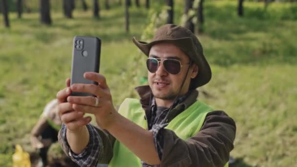 Skrzynia Męskiego Ogrodnika Kaukaskiego Okularach Przeciwsłonecznych Filmującego Się Smartfonie Lesie — Wideo stockowe