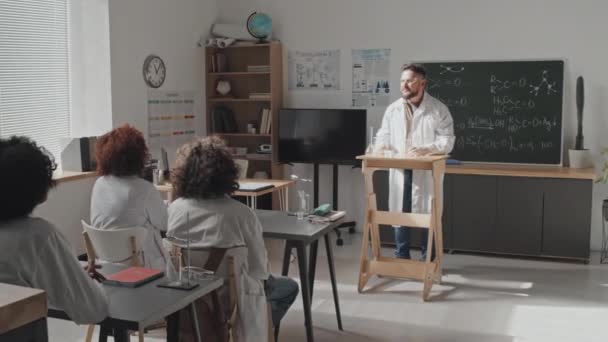 Långskott Manlig Lärare Medicinsk Klänning Och Skyddsglasögon Står Framför Gymnasieelever — Stockvideo
