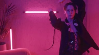 Gözlüklü bir gencin portresinde pembe neon ışıklarla dans edip kameraya bakarken.