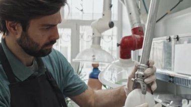 Yüzünde sakal olan, insan kalçasındaki alçı üzerinde protez detay deneyen, ciddi, genç, beyaz bir adamın orta boy yakın çekimi.