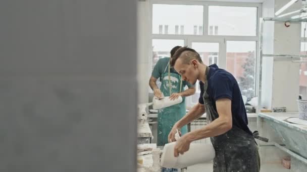 義肢のソケットのための石膏鋳造物を扱う2人の若い成人白人男性 余分な材料を除去し — ストック動画