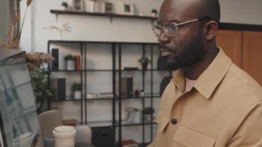 Gündüz vakti ofisteki bilgisayarın klavyesine yazı yazan gömlekli siyahi bir gencin yan bakışını eğiyorum.