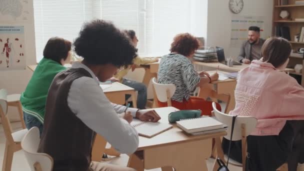 下午坐在课桌边听课 写摘要的聪明的非裔美国人的侧视图 — 图库视频影像