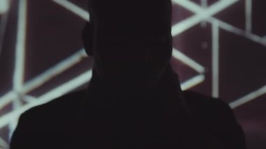 Yakışıklı Afro-Amerikalı adamın yakın çekim yavaşlığı elleriyle boynunu okşuyor sonra mavi neon ışıklı kameraya bakıyor aydınlatıcı, modern kaleydoskopik arka plan