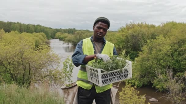 Średni Portret Afroamerykańskiego Ogrodnika Sadzonkami Stojącego Pierwszym Planie Rzeki Lesie — Wideo stockowe