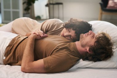 Genç ve huzurlu bir çift sabahları çift kişilik yatakta yatarken kadınlar başlarını kocasının omzunda tutarlar.