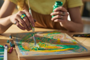 Boya fırçası ve guaj ile genç yaratıcı kadının yakın çekimleri stüdyoda çalışırken kağıt üzerinde yeni sanat eserleri yaratıyor.