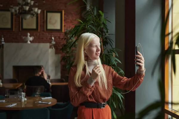 Ευτυχισμένη Νεαρή Γυναίκα Albino Ακουστικά Κοιτάζοντας Την Οθόνη Του Κινητού — Φωτογραφία Αρχείου