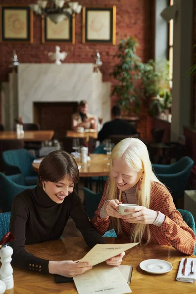 Δύο Νεαρές Χαρούμενες Γυναίκες Casualwear Ανάγνωση Χαρτί Μενού Στο Καφέ — Φωτογραφία Αρχείου