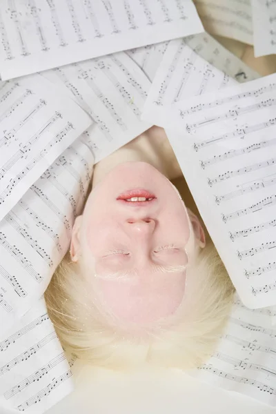 俯瞰着白化病少女躺在充满温水的浴缸里躺在乐谱中苍白的脸庞 — 图库照片