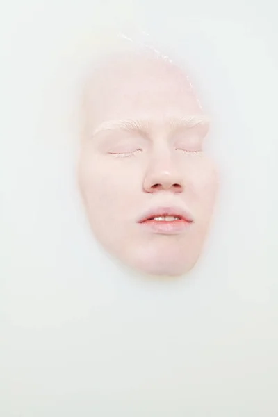 白化病女青年仰卧在温水浴缸中 闭眼享受卫生习惯时脸部以上角度 — 图库照片