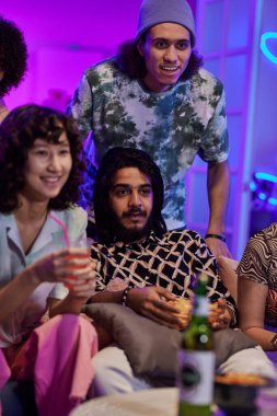 Bir grup genç erkek ve kadın, hafta sonu ev partisi için toplandıkları sırada TV 'de içki içip maç izliyorlar.