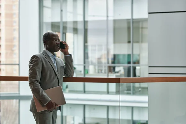 成熟自信的非洲裔美国男性企业家 身穿雅致的灰色西装 在智能手机上与办公室中心的下属之一交谈 — 图库照片
