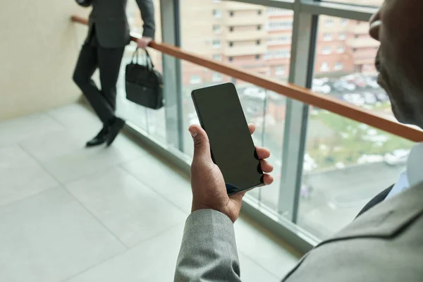 Zbliżenie Strony Czarny Człowiek Trzymając Telefon Komórkowy Przeciwko Młody Biznesmen — Zdjęcie stockowe