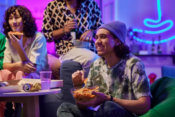 Jovem Feliz Comendo Batatas Fritas Assistindo Filme Enquanto Sentado Contra — Fotografia de Stock
