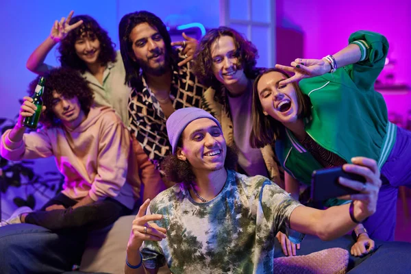 一群年轻快乐的跨文化朋友穿着便服站在被霓虹灯照亮的客厅里 在家里的聚会上自拍 — 图库照片