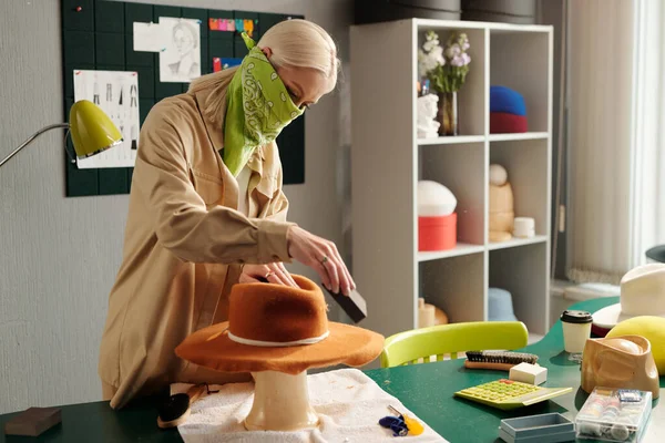 반다나를 여자가 도구를 사용하여 모자를 작업장에서 물품을 가지고 구부리고 — 스톡 사진