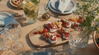 Yüksek açı. Yemek masasından çekilen hiç kimse nefis yemekler, ev yapımı limonata ve açık hava partisi için vazoda kır çiçekleri ile servis yapmaz.