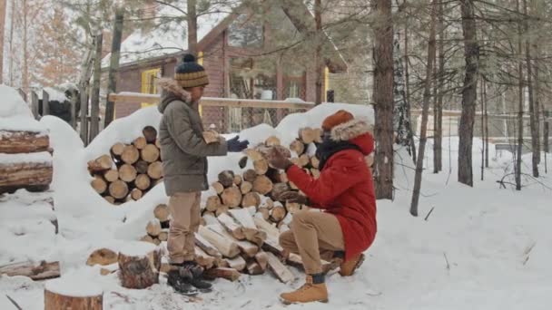 Kışlık Giysili Genç Siyah Baba Karla Kaplı Odunlukta Çömelmiş Oğluna — Stok video