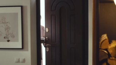 Orta uzunlukta beyaz bir kadın ve adam sessizce apartmana giriyor, koca pastayı tutuyor, gülümsüyor.