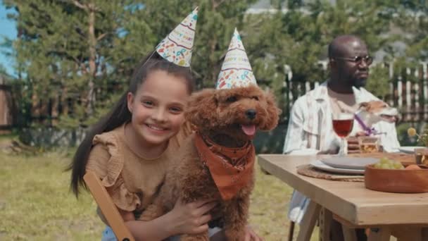 年轻女孩和她的狗戴着生日宴会的帽子 在镜头前摆出一副很高兴的样子 有选择性地拍摄焦点 — 图库视频影像