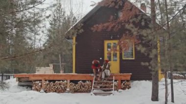 Güzel Afrikalı Amerikalı çiftin, kar yağışlı kış gününde verandada, ahşap kır evinin karşısında otururken görüntüsünü büyüt.
