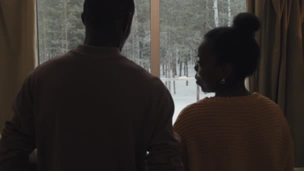 在冬日里 年轻的非洲裔美国男女恋爱中的男子和女子慢慢走向窗户欣赏森林美景 — 图库视频影像