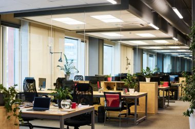 Çalışma alanı boyunca sıralı sandalyeler ve yeşil bitkilerle birlikte uzun koridor boyunca uzanan iş merkezindeki geniş çağdaş ofisin bir parçası