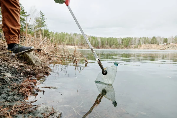 Przycięty Obraz Człowieka Podnoszącego Brudne Plastikowe Butelki Jeziora — Zdjęcie stockowe