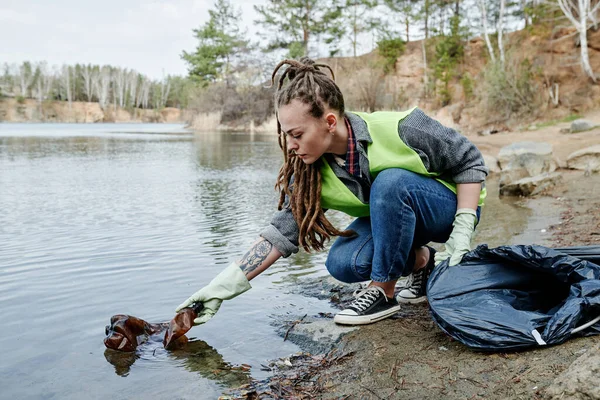 Młoda Kobieta Dredami Wyciągająca Plastikową Butelkę Jeziora Leśnego — Zdjęcie stockowe