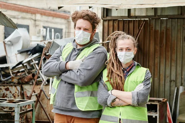 Team of volunteers in protective masks and neon vests ready to sort scrap metal