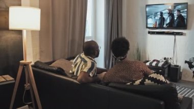 Genç Afrikalı Amerikalı kadın ve erkeğin arka koltukta oturmuş, akşamları TV 'de film izliyorlar.