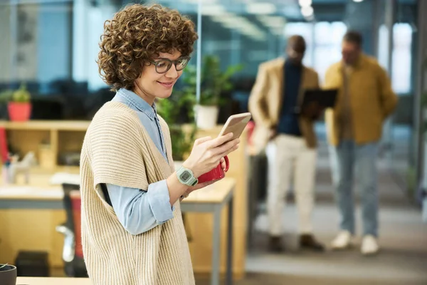 快乐的年轻女性白领 穿着便服 戴着眼镜 用智能手机发短信 和男同事喝咖啡 — 图库照片