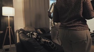 Genç siyahi heteroseksüel çiftin ellerinde şarap ve bir tabak üzümle oturma odasındaki koltukta oturup TV 'de sohbet etmelerini izlemek.