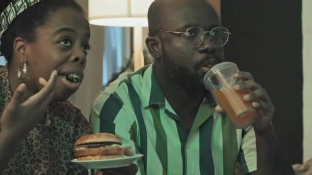 Genç Siyahi Kadın Erkeğin Evde Oturup Gece Televizyon Izlemesi Hamburger — Stok video