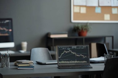 Masanın üzerinde duran, piyasa gelişiminin resimlerini oluşturan analistin iş yeri olan grafik finansal verileri olan dizüstü bilgisayar.