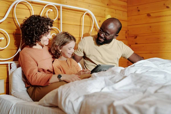 年轻快乐的多文化家庭 父母和他们的儿子 早上带着平板电脑在床上看在线电影或录像 — 图库照片