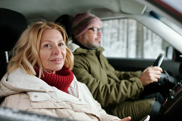 身穿红色保暖针织毛衣和白色冬季夹克的金发女士坐在车里与丈夫相对应 享受周末旅行 — 图库照片