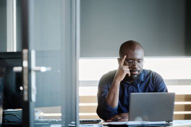 Genç düşünceli işadamı dizüstü bilgisayarın önünde otururken yeni şirketin organizasyonu ve geliştirilmesi hakkında çevrimiçi video izliyor.