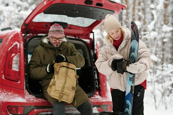 Gammal Blond Kvinna Tittar Snowboard Vintern Resa Medan Hennes Man — Stockfoto