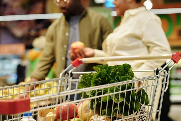 购物车里有新鲜的水果和蔬菜 年轻的夫妇在杂货店里排队时挑选苹果 — 图库照片