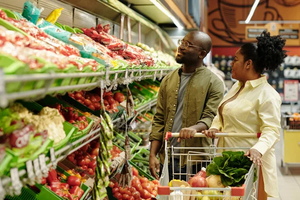 若いアフリカ系アメリカ人のカップルが新鮮な野菜とトマトや他の製品を選択して大規模なディスプレイに立っている — ストック写真