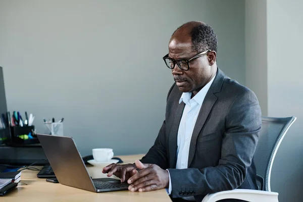 Poważny Dojrzały Afroamerykanin Biznesmen Formalnych Ubraniach Okularach Korzystający Laptopa Siedząc — Zdjęcie stockowe