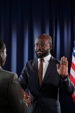 Amerika 'nın yeni başkanı. Sol avuç içi açık vaziyette. Olgun bir adama bakıp sağ elini İncil' in üzerine koyuyor.