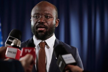 Basın toplantısında gazetecilerin sorularını resmi giyimde kendine güvenen Afrikalı Amerikalı erkek milletvekili veya delege yanıtlıyor